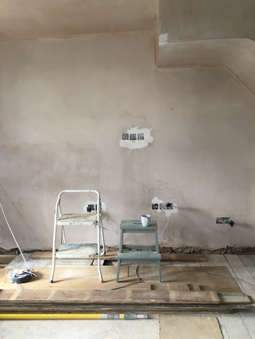 Bare plaster walls with green step ladder and yellow painting pole